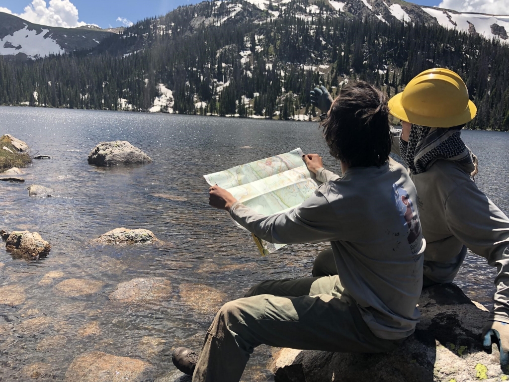 Two people sitting on a rock looking at a map.