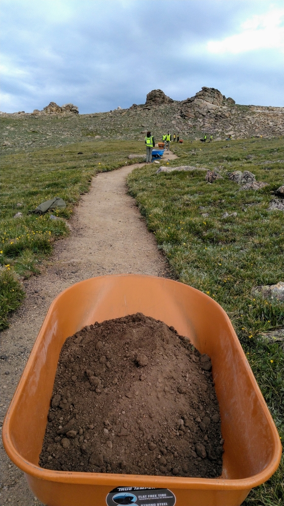 A wheelbarrow full of dirt on a trail.