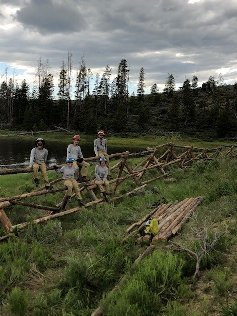 A group of people working on a wooden bridge.