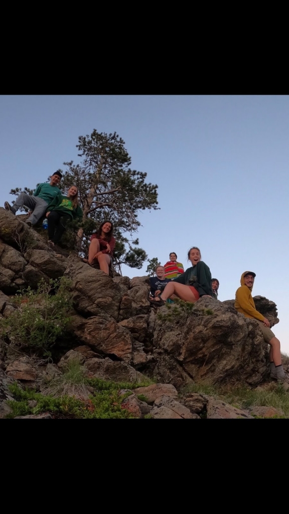Group of people sitting on a rocky hillside and enjoying the outdoors