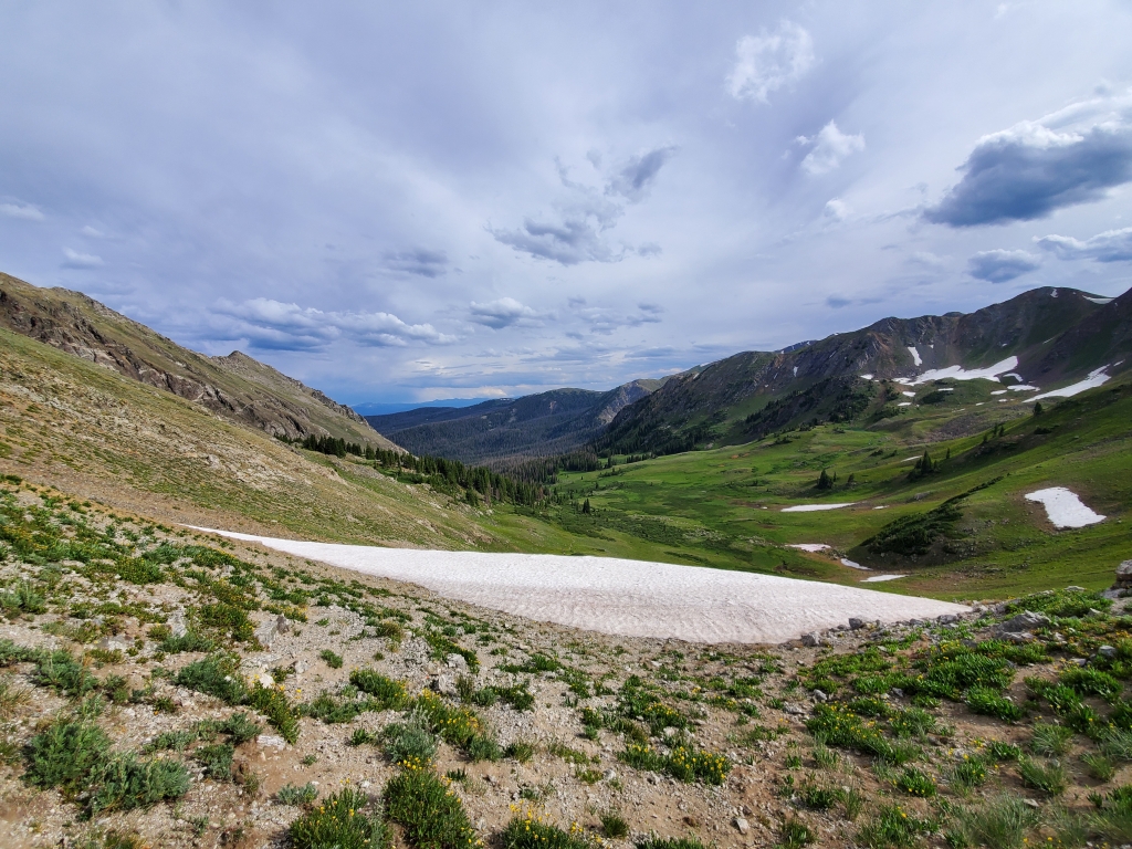 Vast alpine landscape and a clear sky with clouds at a mountain range.