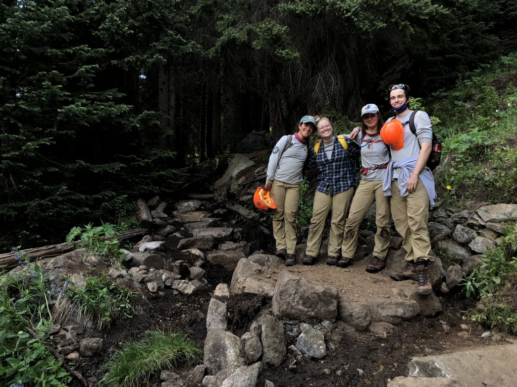 Trail workers posing on a rocky path in a forest