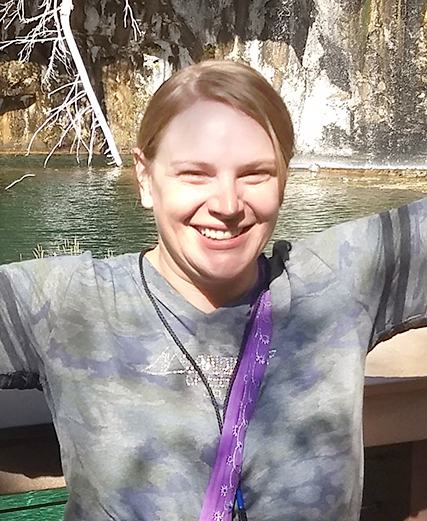 A woman standing in front of a waterfall.