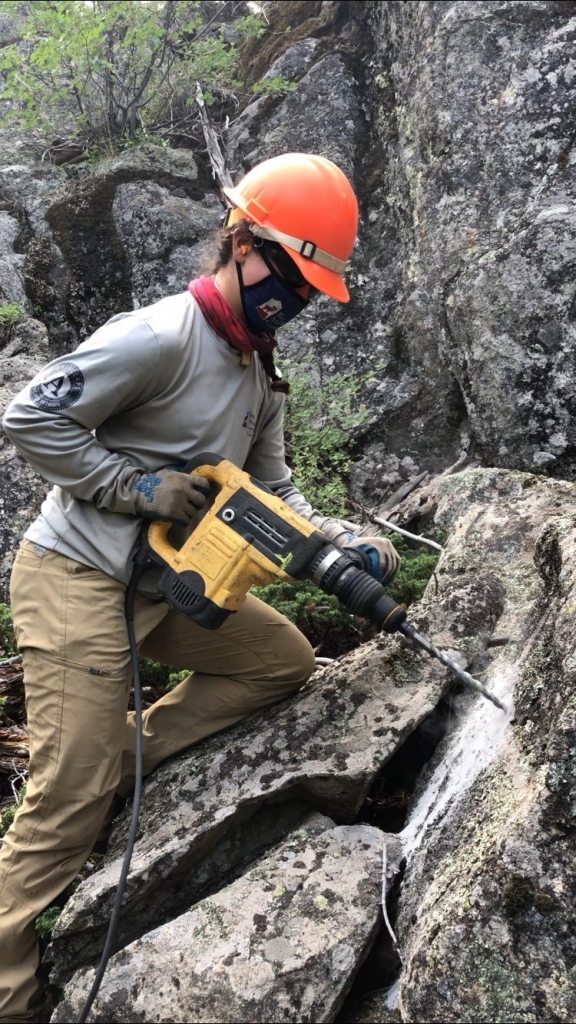 A woman using a drill on a rock.