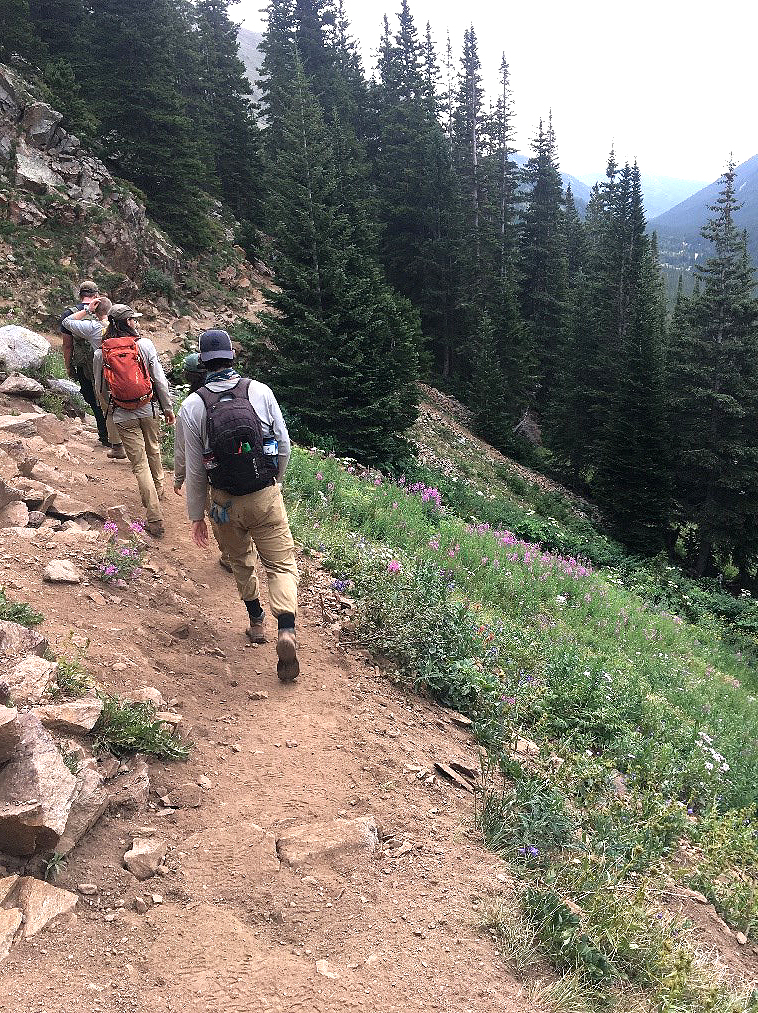 A group of people hiking up a trail in the mountains.