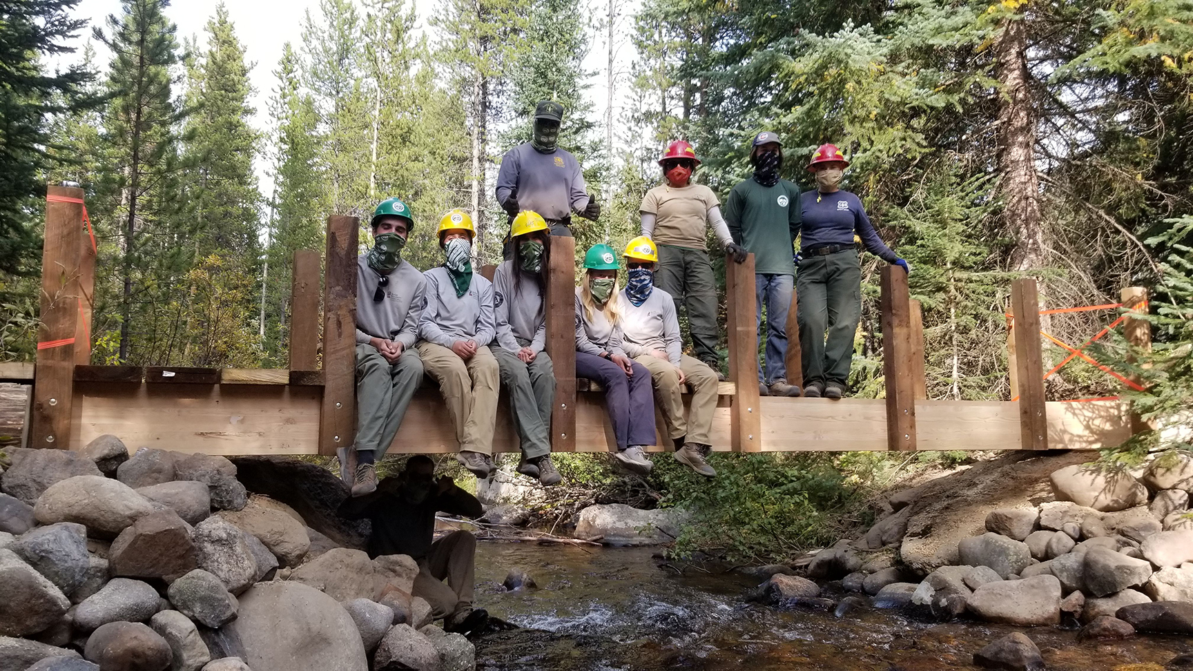 A group of people posing on a wooden bridge.