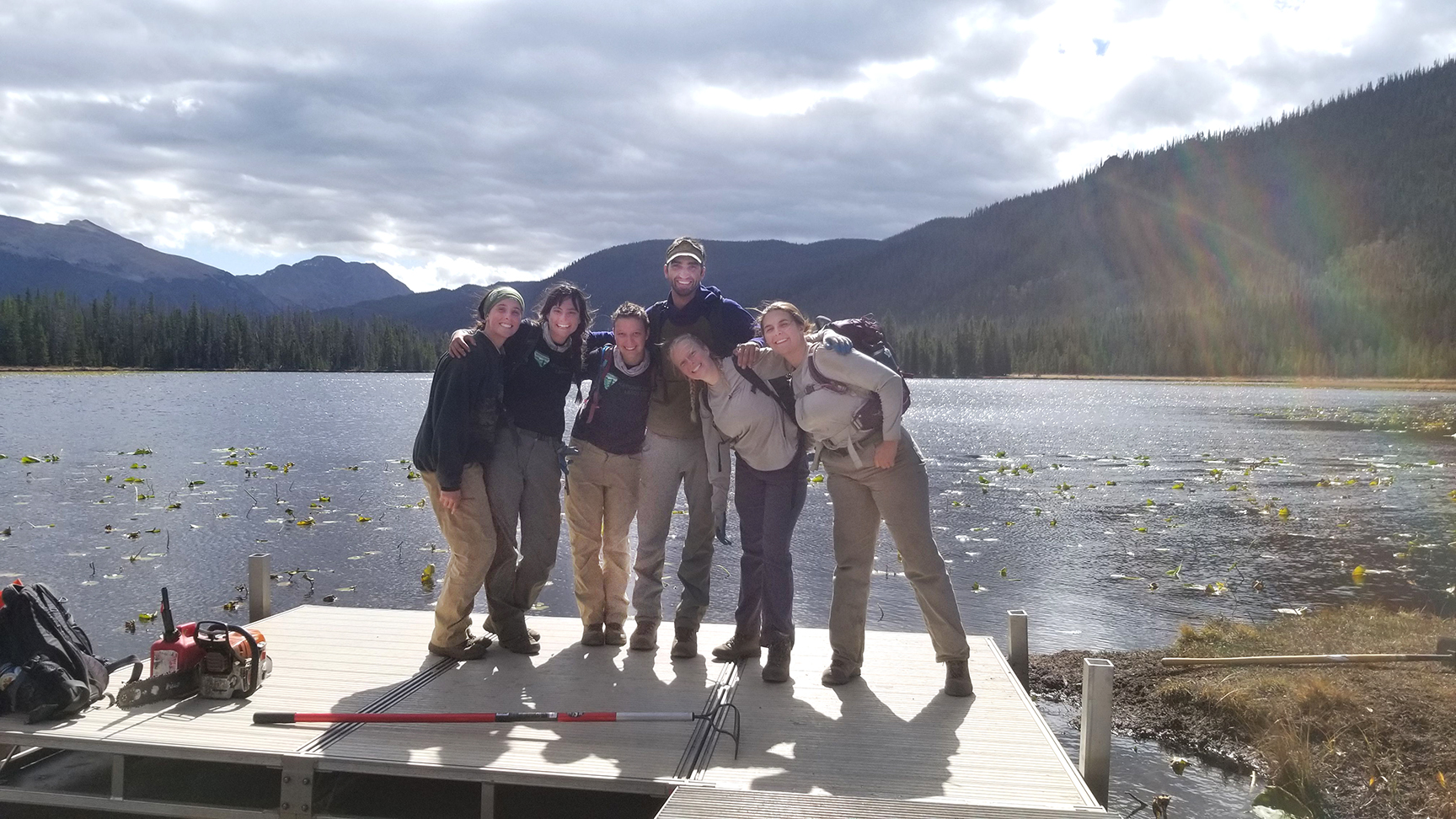 A group of people standing on a dock near a lake.