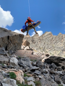 A man in a red jacket is jumping off a rocky cliff.
