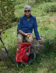 A woman sitting on a rock with a backpack.