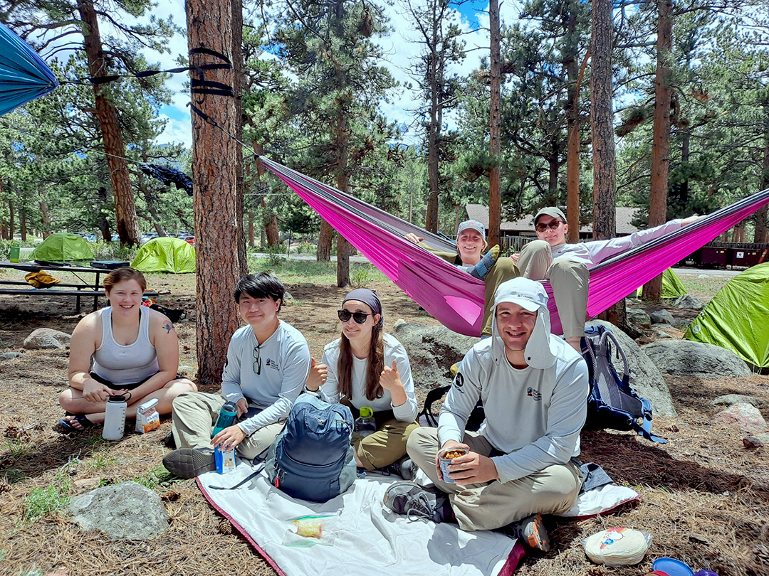Corps members in their natural habitat amongst the trees, tents, and hammocks.