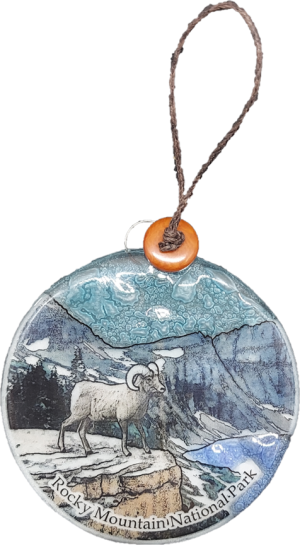 A round RMNP Bighorn Ram ornament with an image of a ram in the mountains.