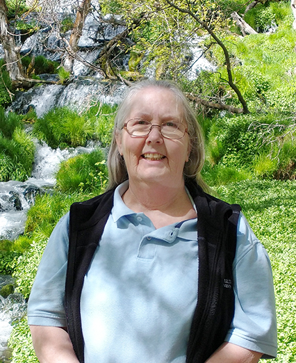 A woman standing in front of a waterfall.