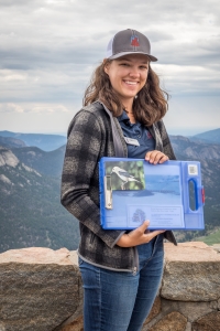 A woman holding a folder in front of a mountain.