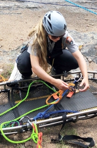 A woman is preparing a harness for a climber.