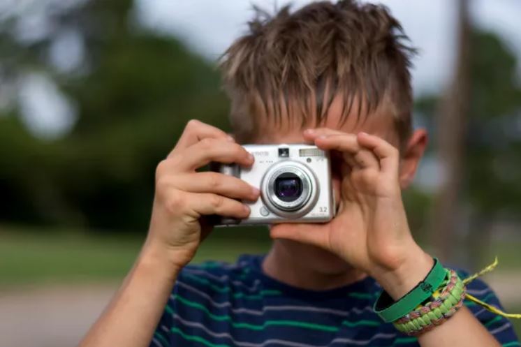 A boy is taking a picture with a camera.