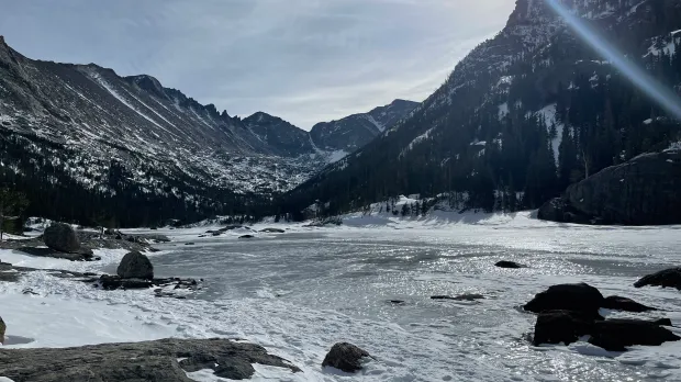 A lake in the mountains with snow on the ground.