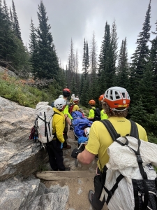A group of people carrying a person up a rocky path.