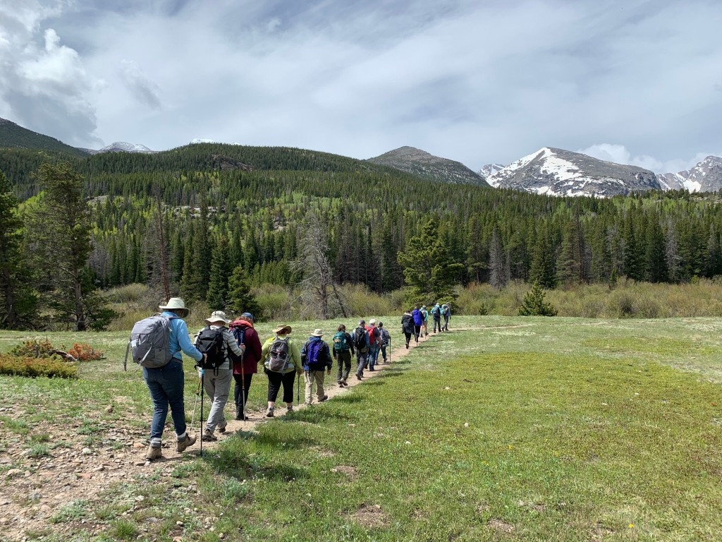 Group of hikers walking in a single file through a mountainous landscape.