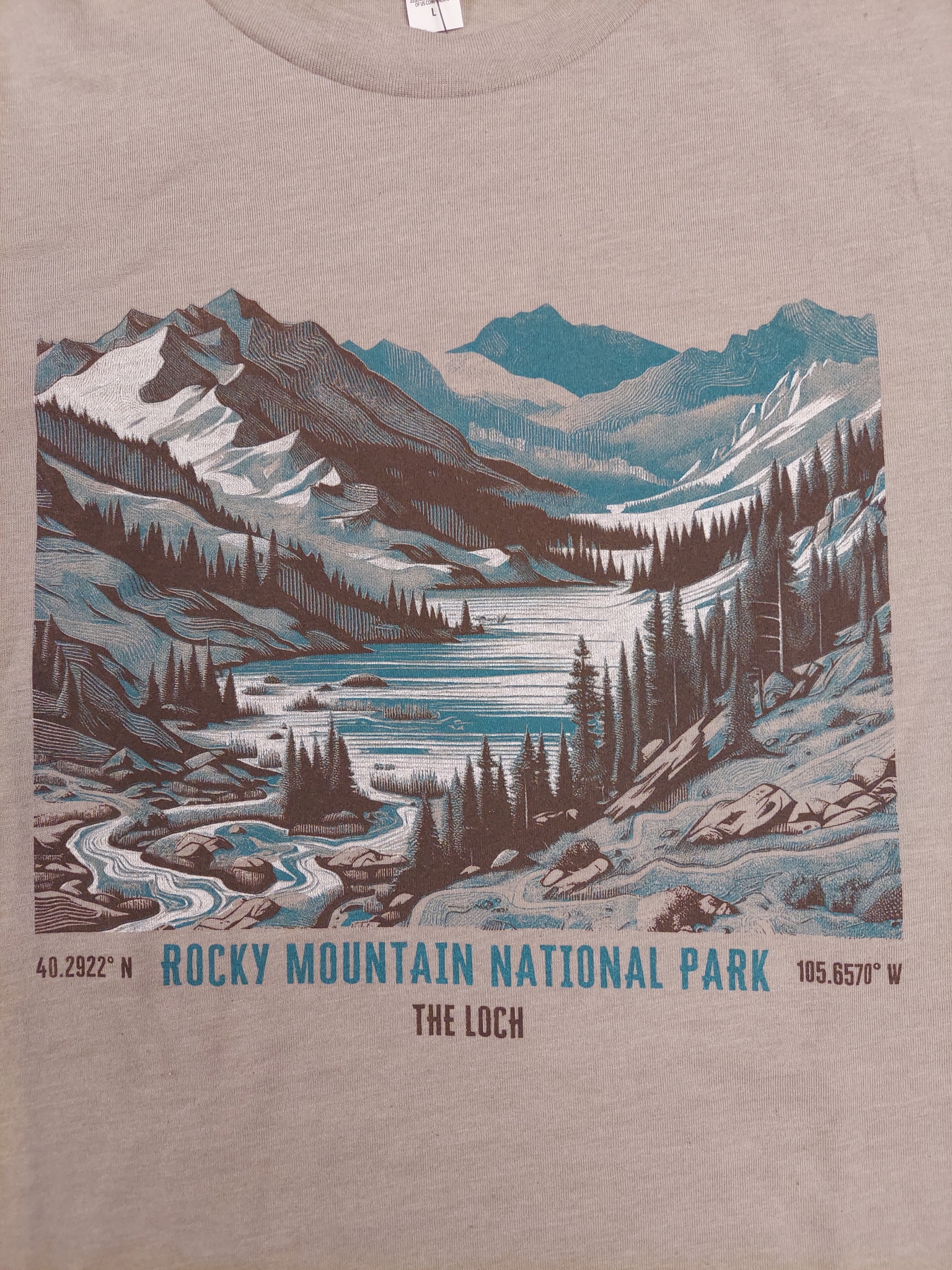 A T-Shirt - RMNP The Loch Vale featuring a scenic illustration of Rocky Mountain National Park's The Loch, with coordinates 40.2922° N, 105.6570° W depicted below.