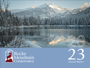 Snow-covered mountains and pine trees reflected in a calm lake with the Rocky Mountain Conservancy logo and text "2023 Annual Report" in the foreground.