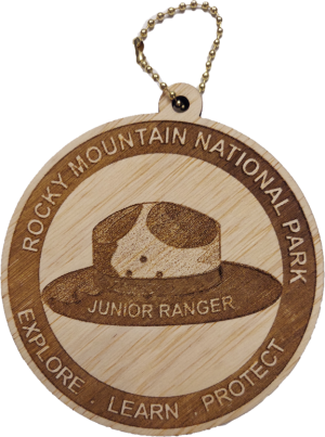 The Ornament - RMNP Junior Ranger Hat is a wooden keychain featuring the Rocky Mountain National Park logo with a ranger hat and the words "Junior Ranger. Explore. Learn. Protect" engraved.