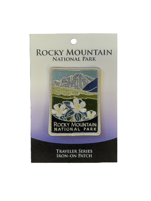 An iron-on embroidered patch from the RMNP Traveler Series showcases a mountain and flowers design, with packaging labeled accordingly.